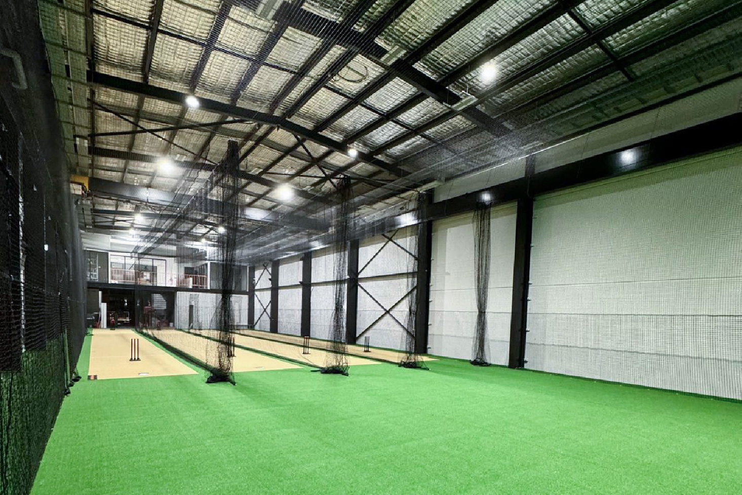 Warehouse converted into indoor cricket lanes with turf and netting