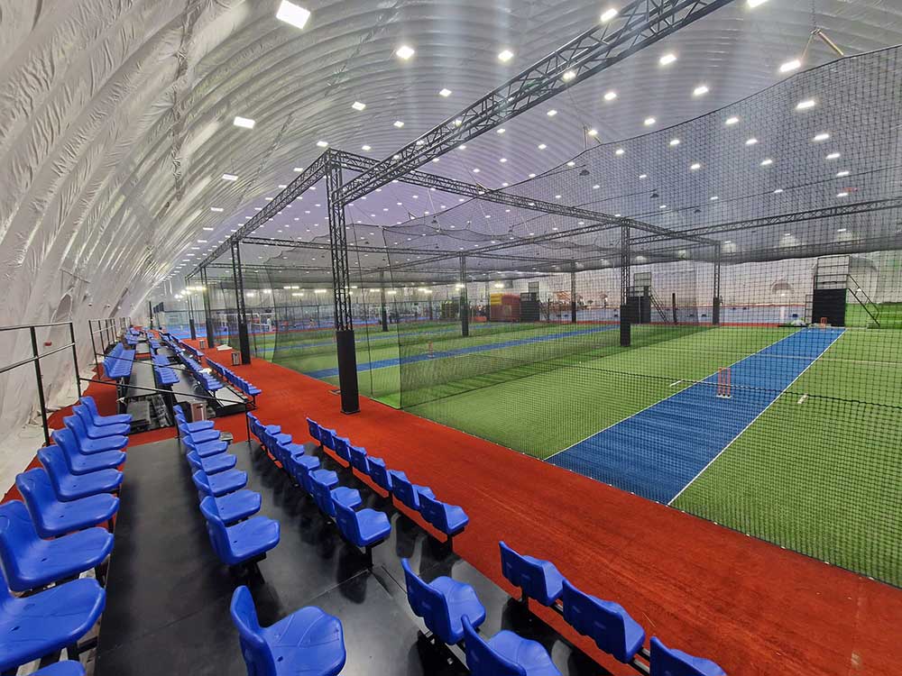 Indoor cricket arena with match courts, netting and spectator seating after conversion