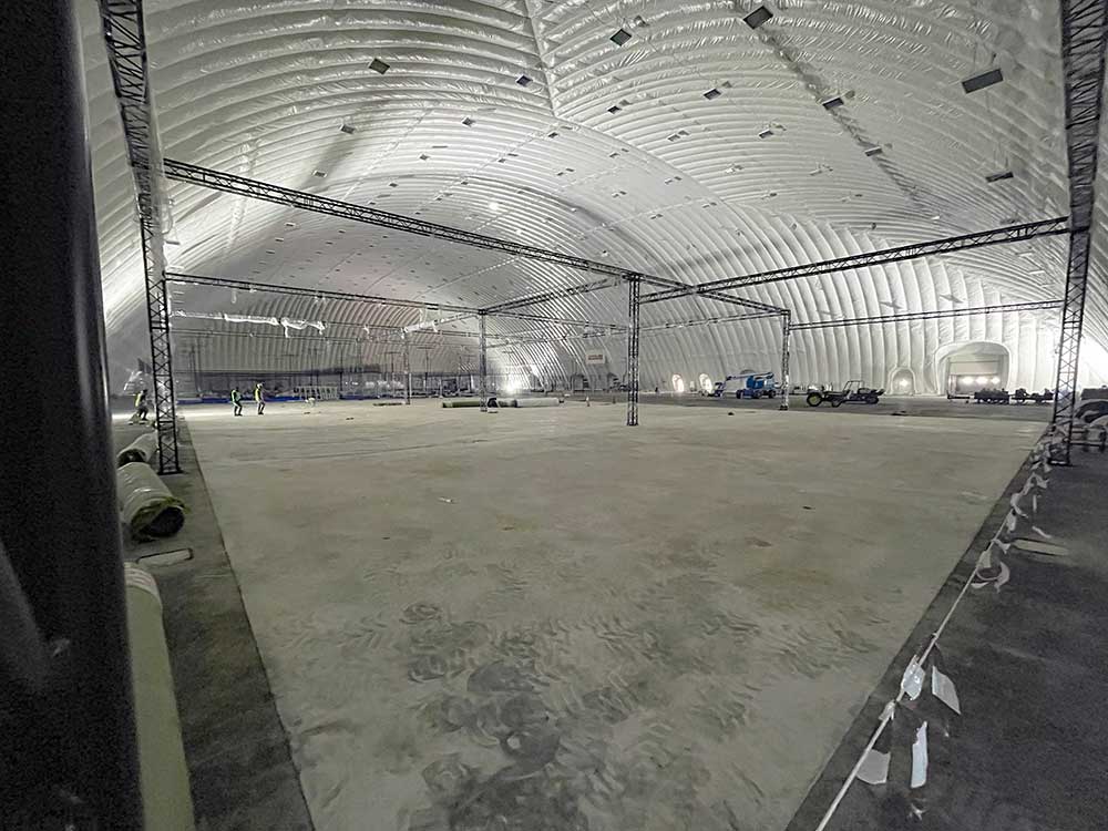 Empty air dome with bare concrete floor and truss frames before conversion