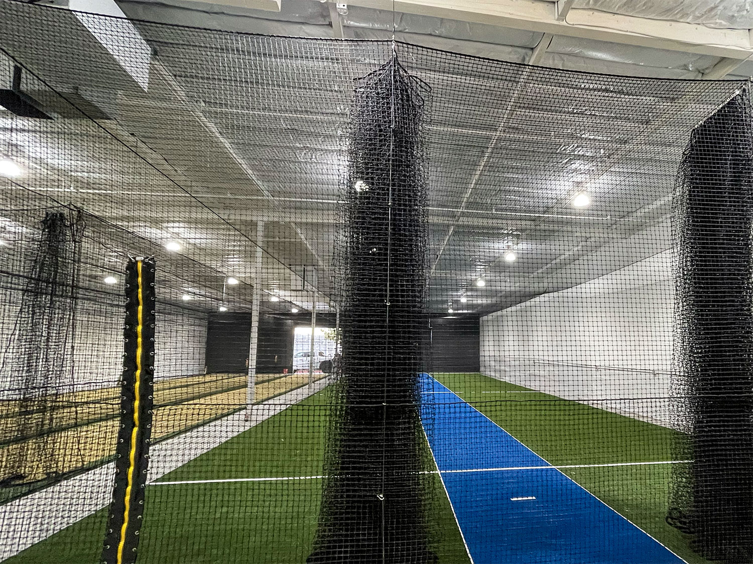 Finished practice lanes with turf, blue wicket surface and netting at Strikers Academy